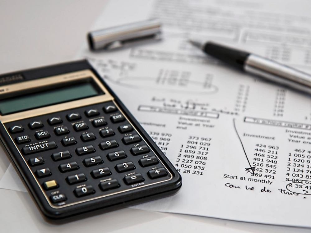 Calculatrice financière posée sur un tableau de chiffrage annoté à la main